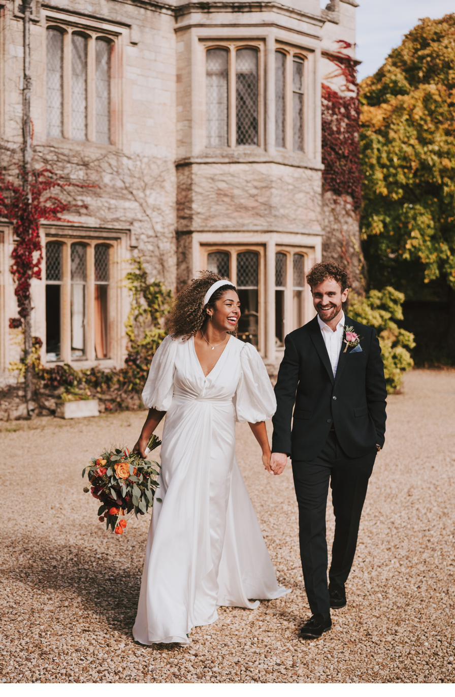Couple hand in hand outside the ivy clad manor house, Dionne and Alistair's manor house wedding in Lincolnshire