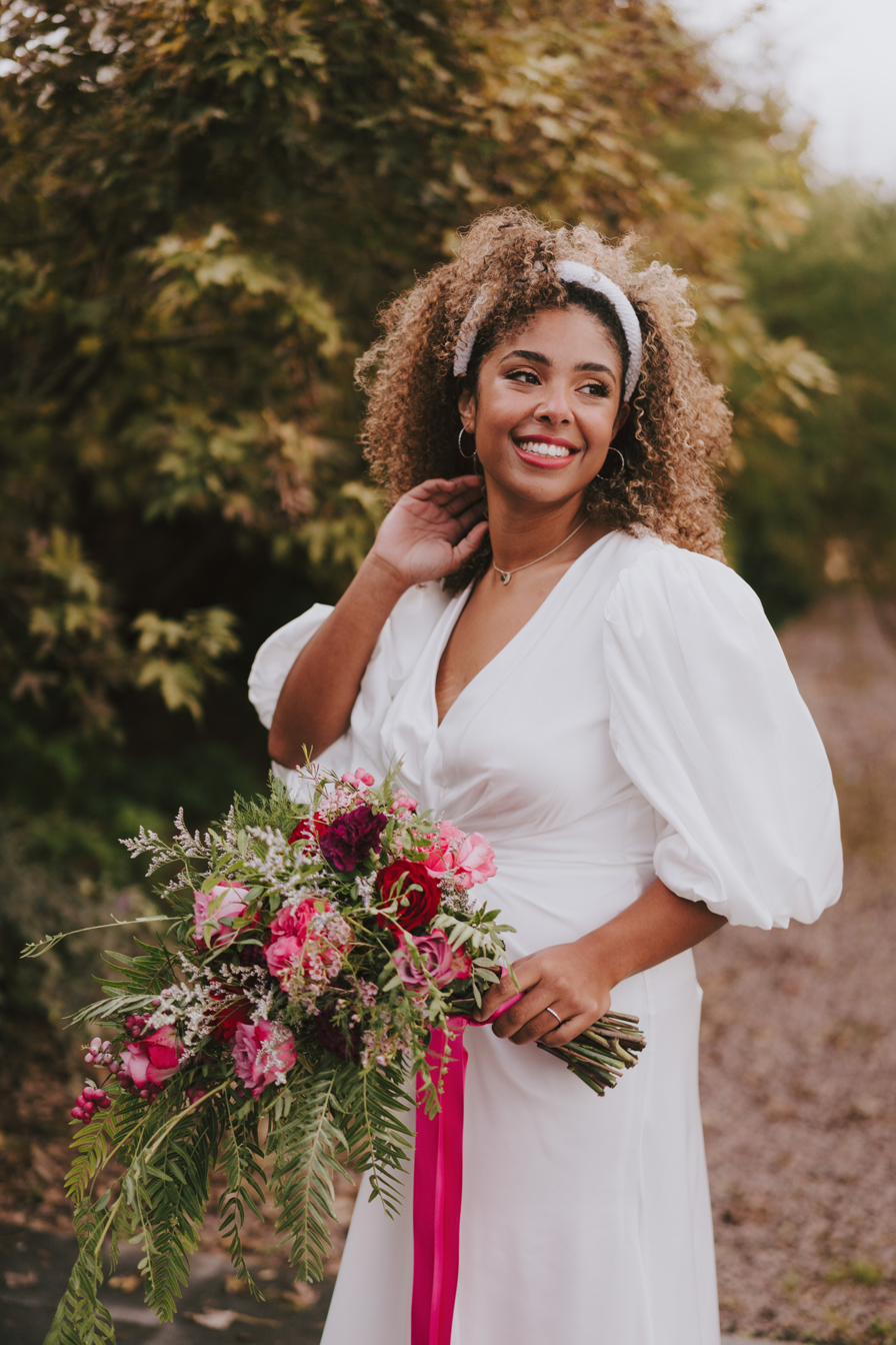 Bride with a pink and raspberry bouquet and trailing ribbon, Dionne and Alistair's manor house wedding in Lincolnshire