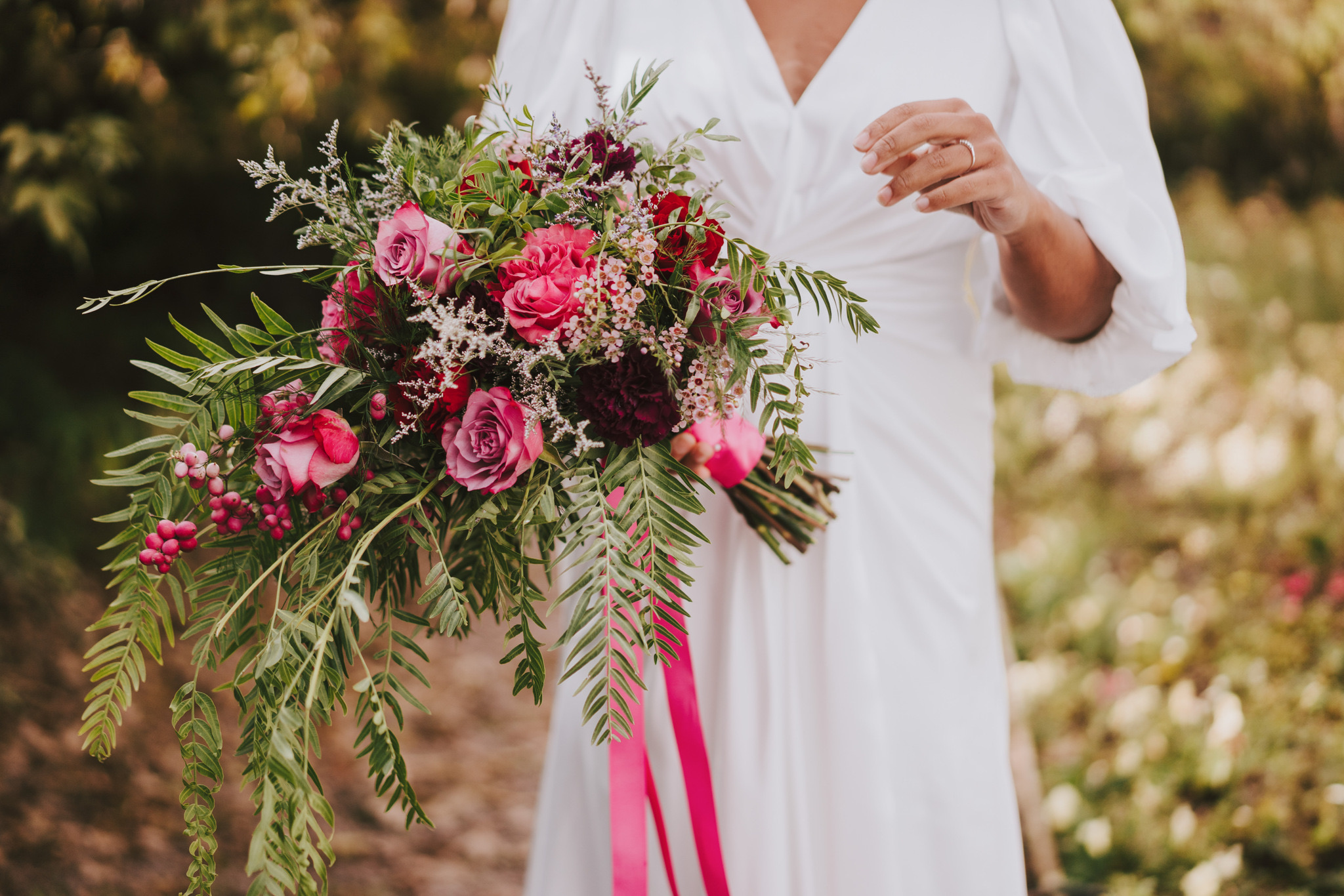 Bright pink rose and berry bridal bouquet with trailing ribbon, Dionne and Alistair's manor house wedding in Lincolnshire