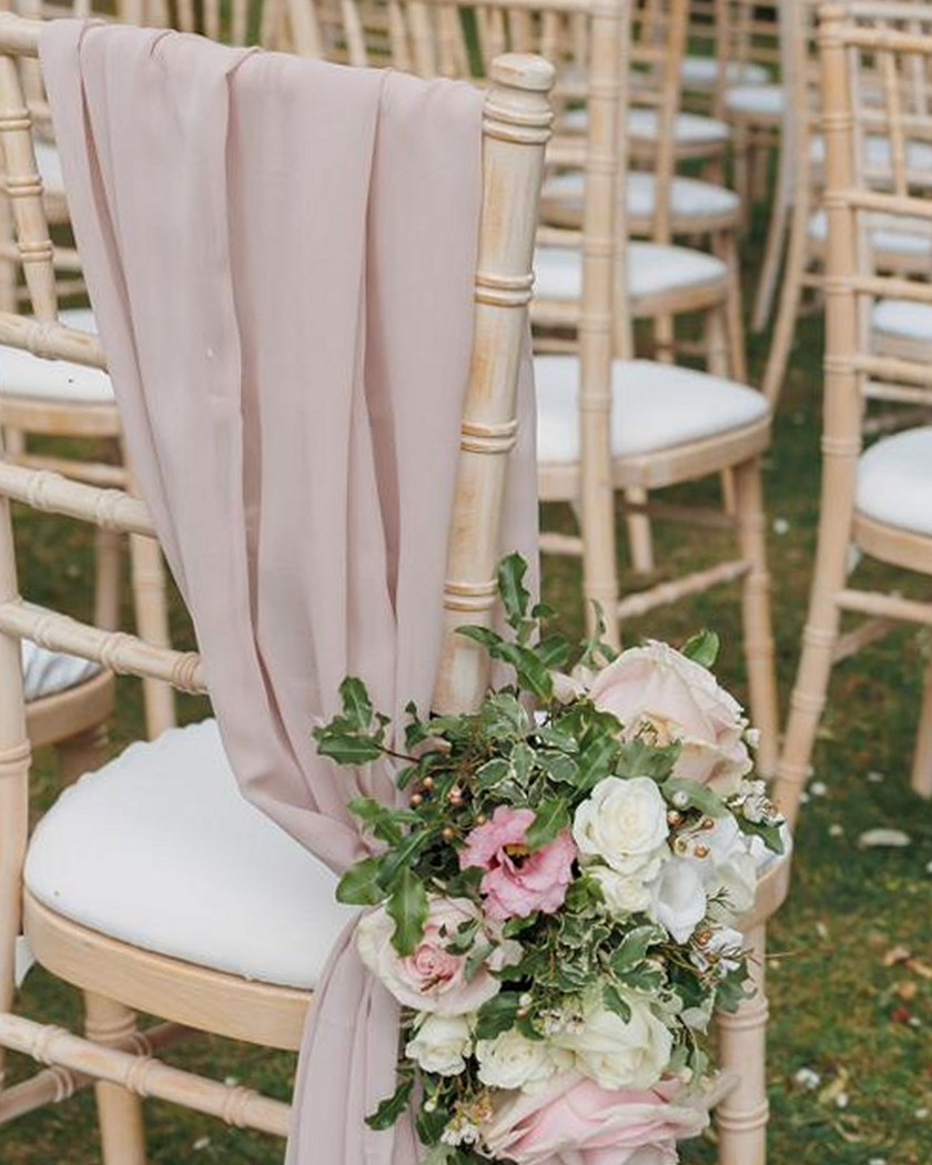 Hired chiavari chairs dressed with drapes and a pew end floral arrangement, Rutland
