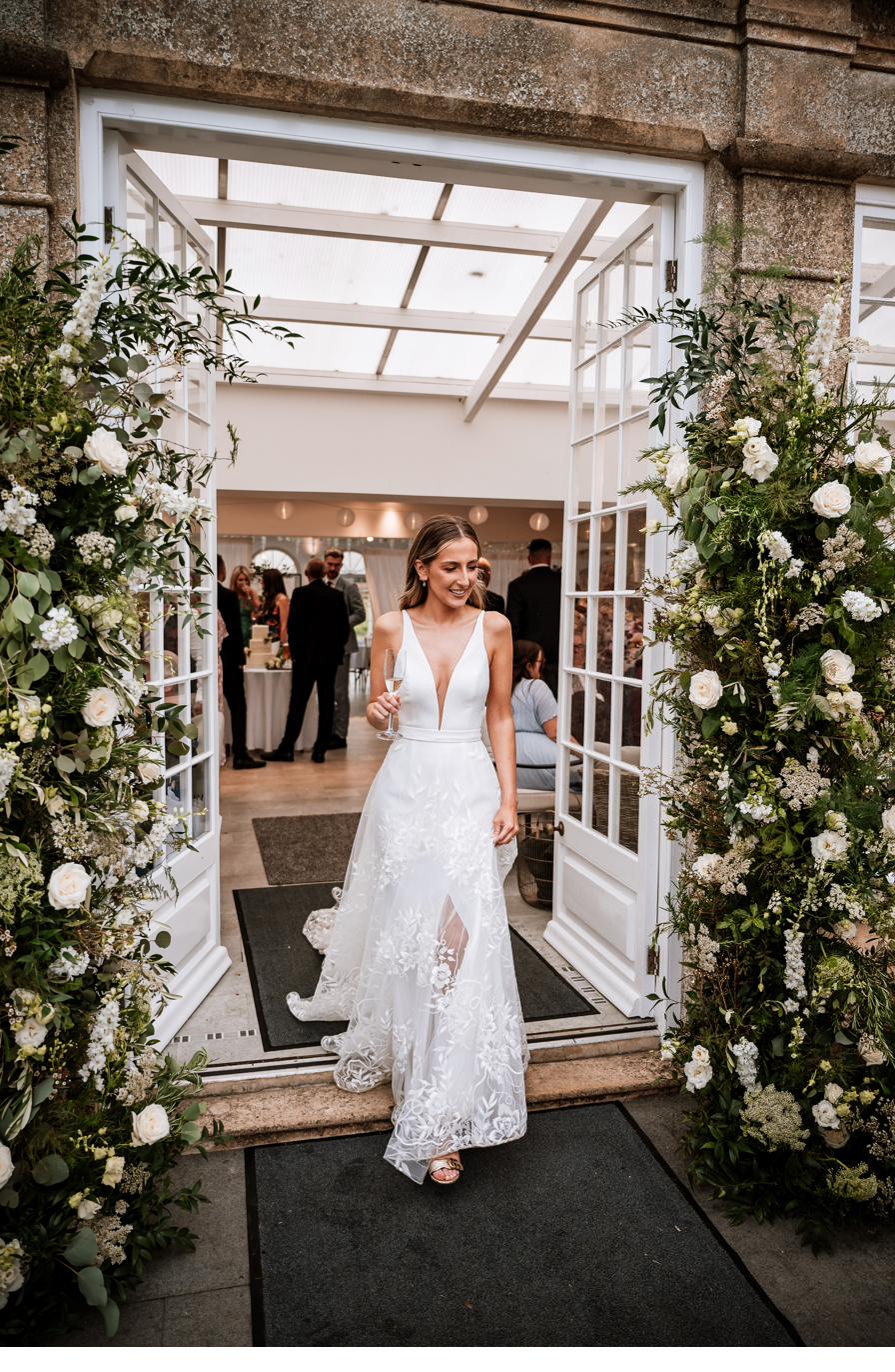 Bride walking through a floral doorway arch, Lincolnshire wedding