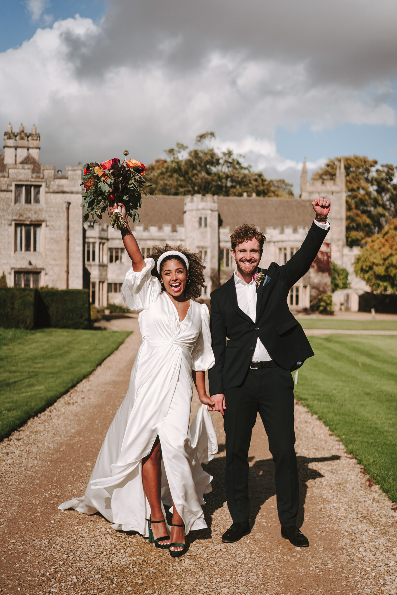 Bride and groom cheering on the drive, Dionne and Alistair's manor house wedding in Lincolnshire