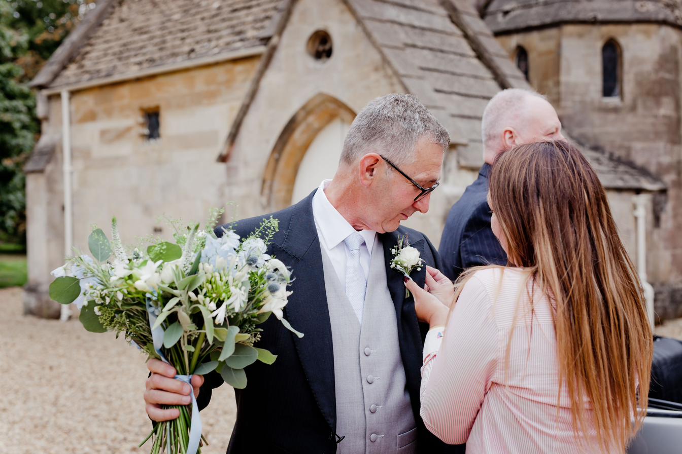 Buttonhole being pinned at a village church, Lincolnshire wedding